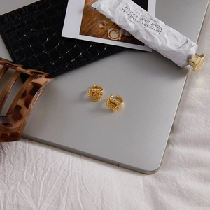 Detailed close-up of golden daisy ear clips arranged with modern lifestyle accessories