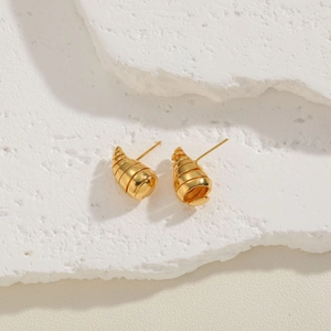 Macro shot of 14K gold plated spiral earrings on a minimalist white stone surface