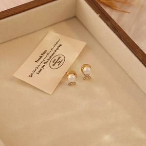 Elegant gold bow earrings with pearls and rhinestones in a velvet jewelry box