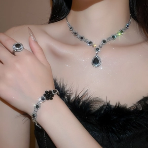 Detailed view of silver necklace and ring set with black teardrop rhinestones on model