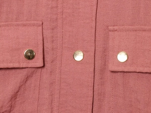 Detail of pink woven jacket featuring high-quality stitching and round gold metal buttons