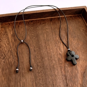 Macro view of flower-shaped black resin pendant with adjustable wax rope on wood tray