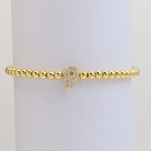 Detail shot of golden beaded bracelet with shimmering zircon-paved letter P charm