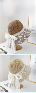 Detail of crochet straw hat featuring floral lace embroidery and large mesh bow decoration