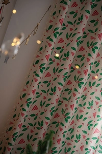 Detail of Christmas curtain with holly leaves, red berries and beige lace trim