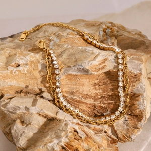 Detail of double-layer gold tennis bracelet with shimmering crystals on a natural stone base