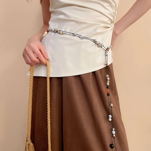Detailed close-up of ethnic beaded waist chain with leather and shell accents on model