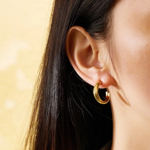 Close-up of polished gold-finished double-layer C-shaped hoop earrings on a model