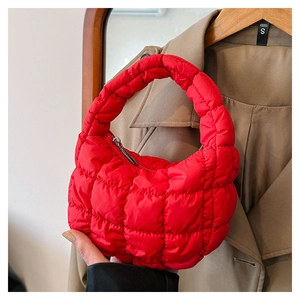 Detailed view of a red quilted puffy cloud bag held by a model for a chic winter look