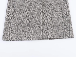 Gros plan sur la texture du tissu à chevrons noir et blanc et les détails de l'ourlet du manteau