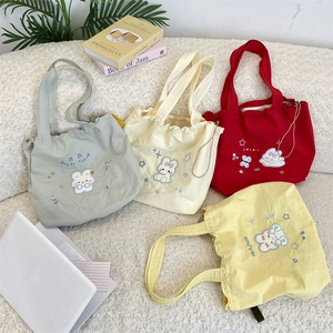 Flat lay of canvas drawstring tote bags featuring cute rabbit embroidery in four colors
