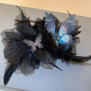 Detail of luxury hair claw featuring black mesh, feathers, and a silver rhinestone butterfly
