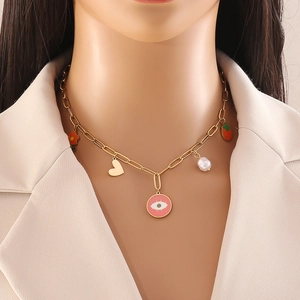 Close-up of gold chain necklace with heart, eye, pearl and strawberry charms on model
