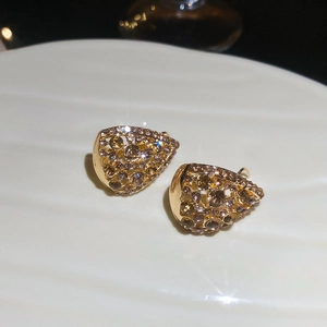 Detailed shot of teardrop hollow earrings with champagne rhinestones on a white plate
