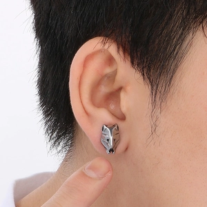 Close-up of a wolf head stud earring in gunmetal finish on a model's ear