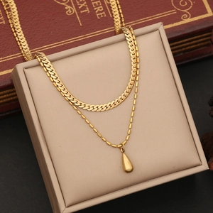 Detail of a double-layered gold necklace with teardrop pendant on a jewelry gift box