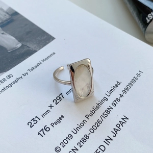 Detail of S925 sterling silver open ring with oval white shell inlay on book background