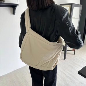 Quilted beige puffer tote bag shown on shoulder in a minimalist indoor setting