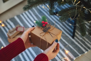 Detail of Christmas gift box in brown kraft paper with pine needles and red berries