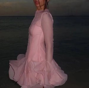 Close-up of pink long sleeve dress featuring layered ruffle hem and button details