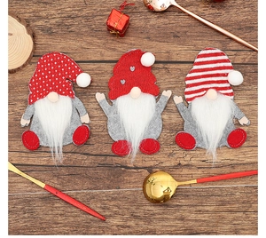 Detailed view of three festive Christmas gnome silverware holders on a wooden background