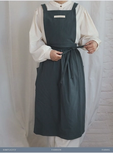 Detail of dark green cotton apron featuring a slogan patch and large practical pockets