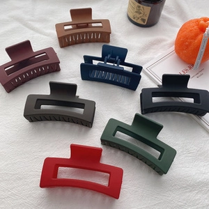 Close-up of matte rectangular hair claws in seven colors on a white linen table