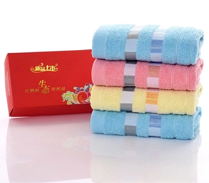 Four-piece cotton towel set in sky blue, pink, and yellow inside a red gift box