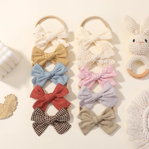 10-piece set of elastic baby headbands featuring colorful fabric bows on beige background