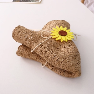 Detail of a foldable straw sun hat with a decorative yellow sunflower and adjustable strap