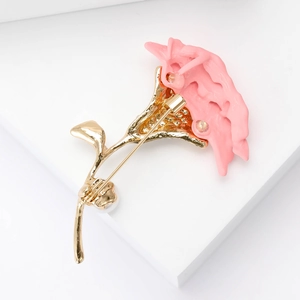 Detail of golden carnation brooch back showing safety pin clasp and pearl accents