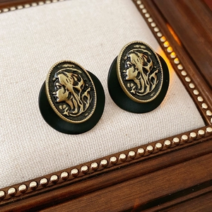 Nahaufnahme der Vintage-Cameo-Ohrringe mit goldenem Porträt und schwarzem Rahmen
