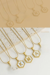 Macro view of gold stainless steel necklace with hexagonal shell initial pendants