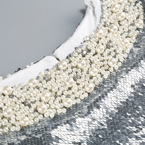 Detailed view of silver sequins, white pearls, and rhinestones on a backless evening gown