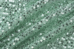 Detail of light green mesh fabric with shimmering silver sequins on bodycon dress