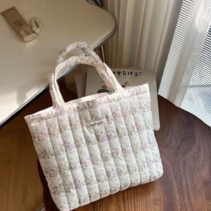 Detail of floral rabbit quilted cotton handbag showing texture on a wooden chair