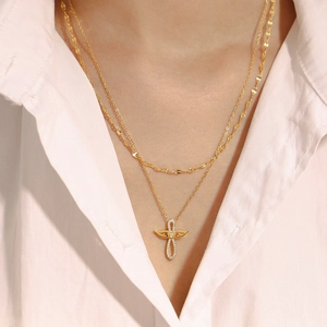 Collier double épaisseur en or avec ailes d'ange et croix en zircon sur un mannequin