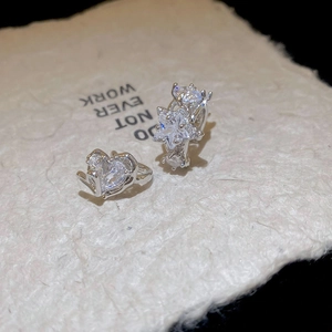 Macro shot of silver zircon heart and star rings on textured light beige paper