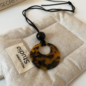 Close-up of vintage amber round pendant with tortoise pattern on beige linen pouch
