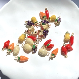 Colorful alloy fruit and vegetable charms for DIY jewelry making on white ceramic plate