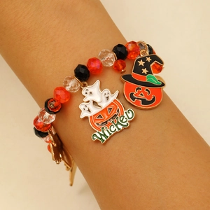 Detalle de una pulsera de Halloween con dijes de calabaza y fantasma en la muñeca de una modelo