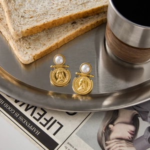 Vintage gold coin earrings with large pearls on a brushed metal tray with coffee and toast