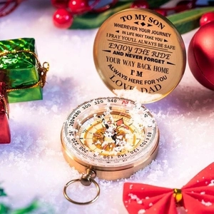 Detailed view of an engraved brass compass gift for son with festive holiday background