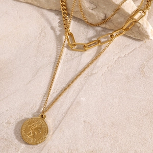 Layered gold stainless steel coin pendant necklace on white marble texture surface