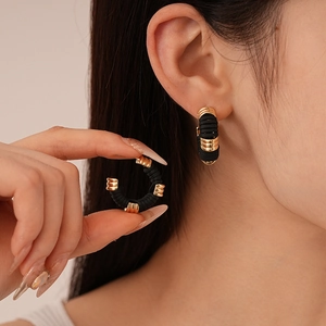 Gros plan de boucles d'oreilles en cuir artificiel en C avec texture nervurée et clous dorés