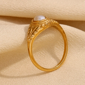 Macro shot of gold-plated flower pattern ring with a glossy white pearl on beige fabric
