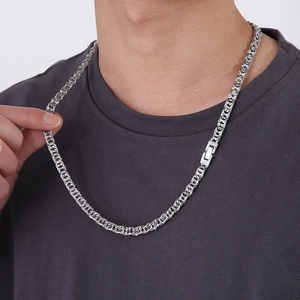Detail of a polished silver titanium steel woven chain necklace worn by a male model