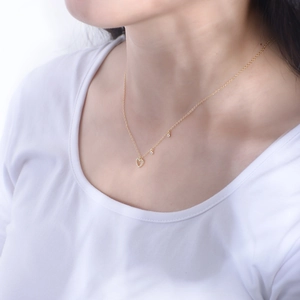 Detailed close-up of a golden heart pendant necklace with diamonds on a model neck