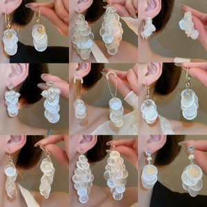 Collage de boucles d'oreilles en nacre et perles dorées et argentées sur modèle