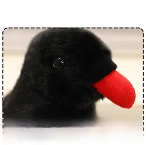 Close-up of plush magpie doll featuring soft black fabric and a vibrant red beak detail